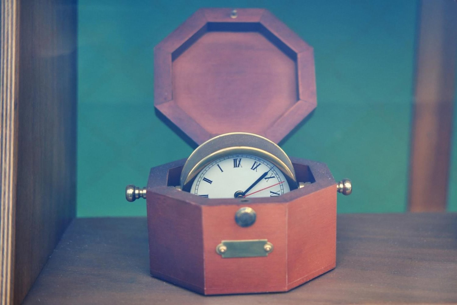 Antique wooden watch safe with a clock face displayed inside a glass cabinet